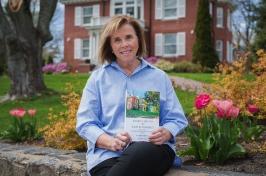 Jan Dean sitting outside of the president's house with her book